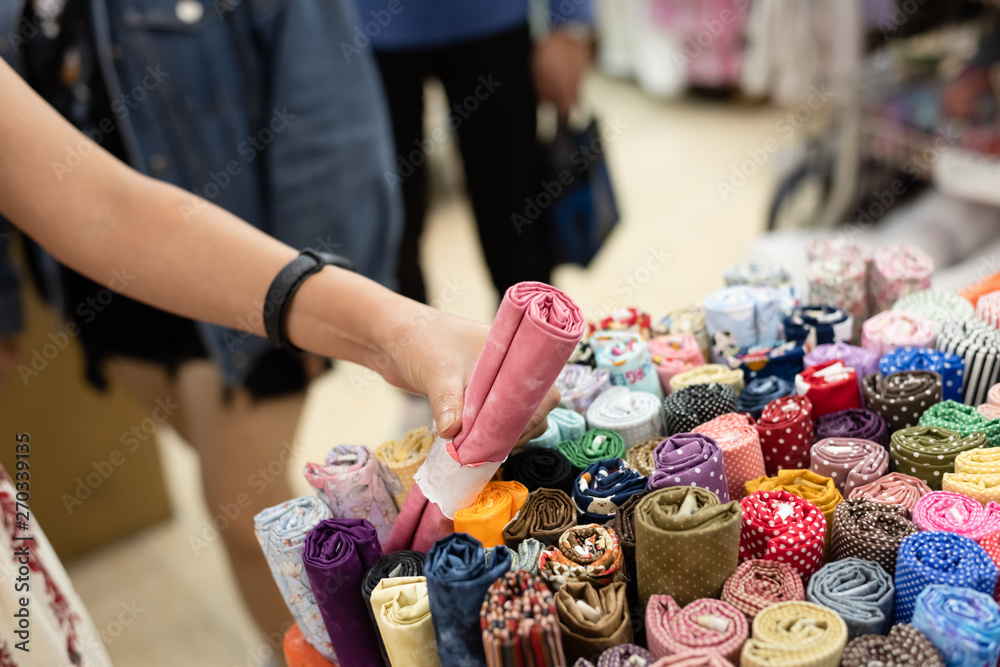 Obraz premium kobieta wybiera rolkę materiału w sklepie z tkaninami