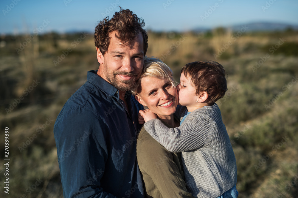 Young family with a small daughter standing outdoors in nature in Greece. Young family with a small daughter standing outdoors in nature in Greece.