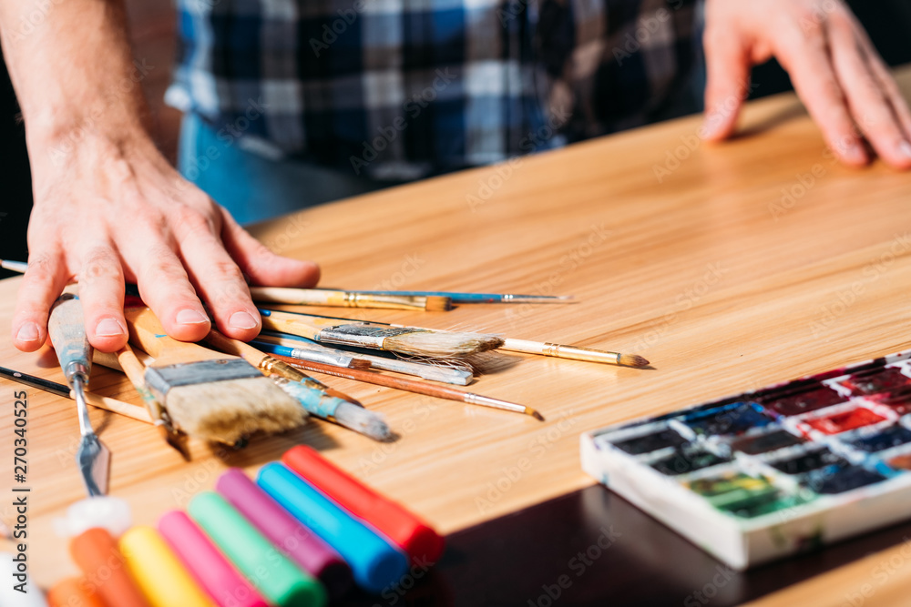 Artist tools. Paints paintbrushes markers arrangement. Man at workplace. Art studio. Creative process occupation lifestyle.