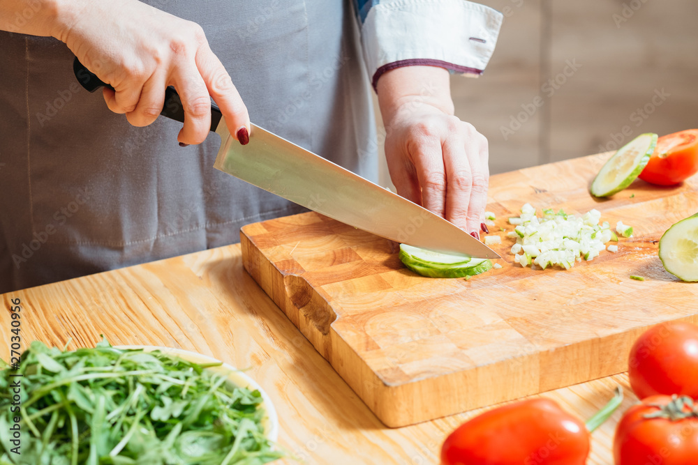 Woman hands cutting chopping cucumber closeup. Organic fresh veggies for healthy balanced vegetarian salad. Dieting. Woman hands cutting chopping cucumber closeup. Organic fresh veggies for healthy balanced vegetarian salad. Dieting.