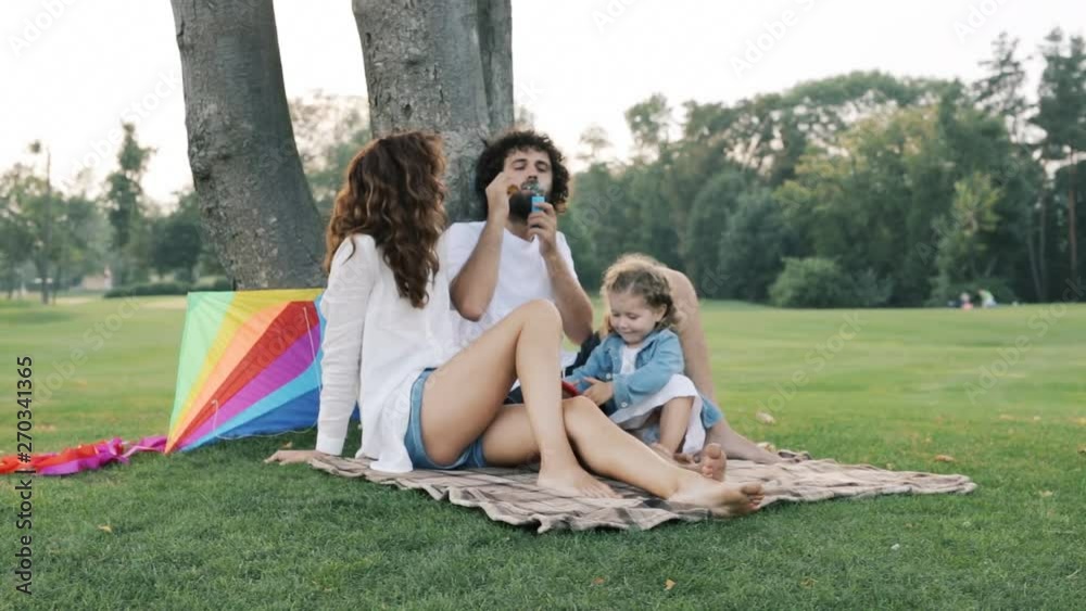 Little kid girl playing with bubble blowers. Happy family outdoors in the park. Slow motion. Little kid girl playing with bubble blowers. Happy family outdoors in the park. Slow motion.