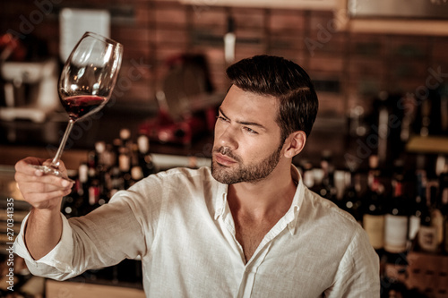 Young brunette man looking at glass of wine