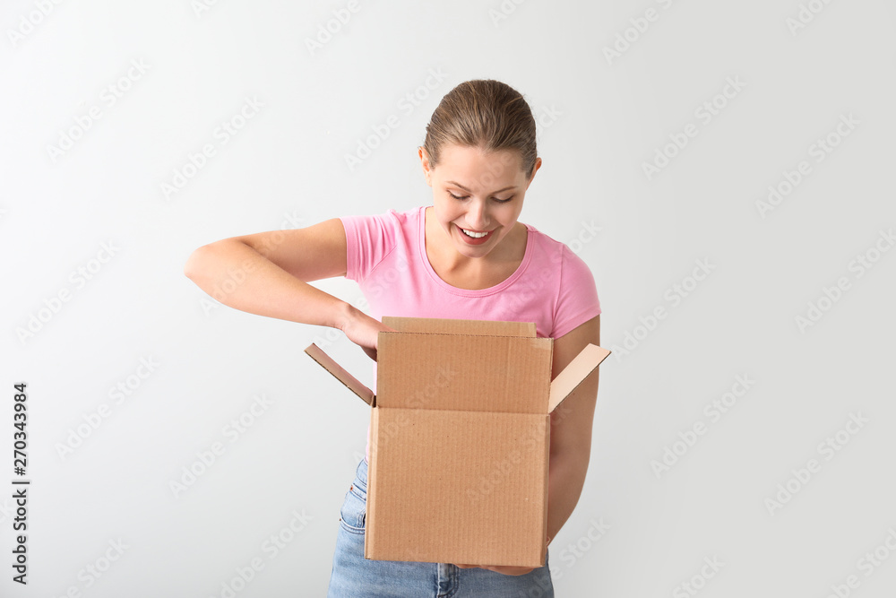 Young woman with cardboard box on light background Young woman with cardboard box on light background