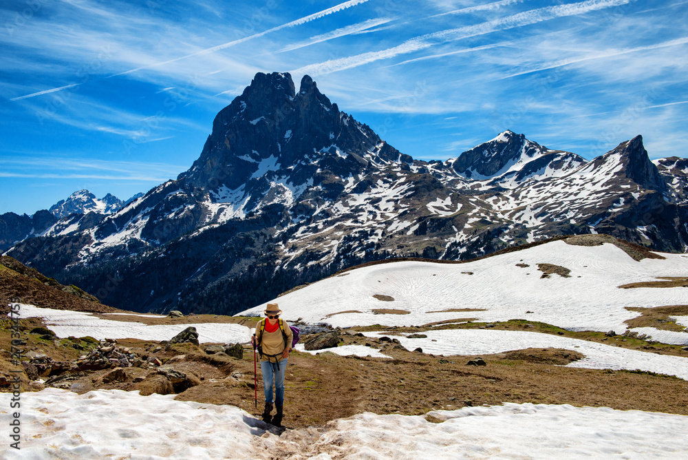 hiker woman walking in the french Pyrenees mountains, Pic du midi d Ossau in background