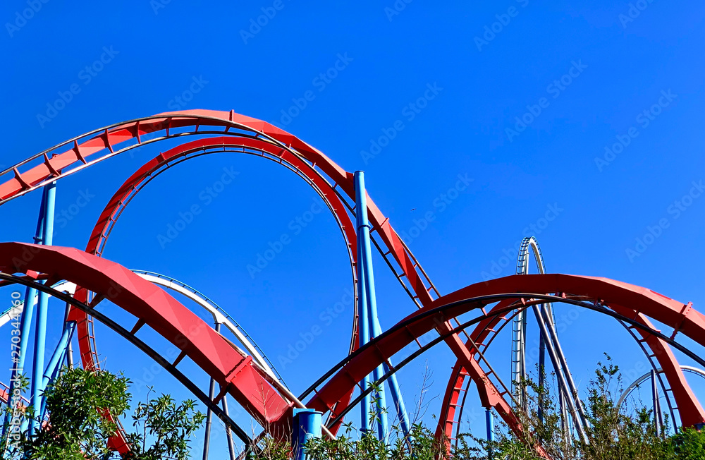 Fototapeta premium A red roller coaster in a amusement park with some loopings