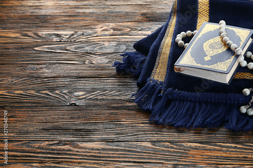 Photography Muslim prayer mat, beads and Koran on wooden background