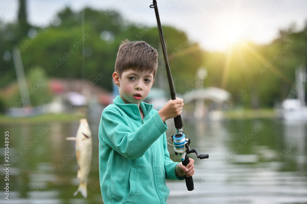 kid boy hold a fish on fishing rod kid boy hold a fish on fishing rod