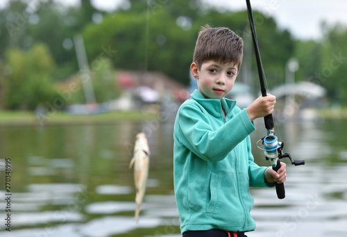 kid boy hold a fish on fishing rod
