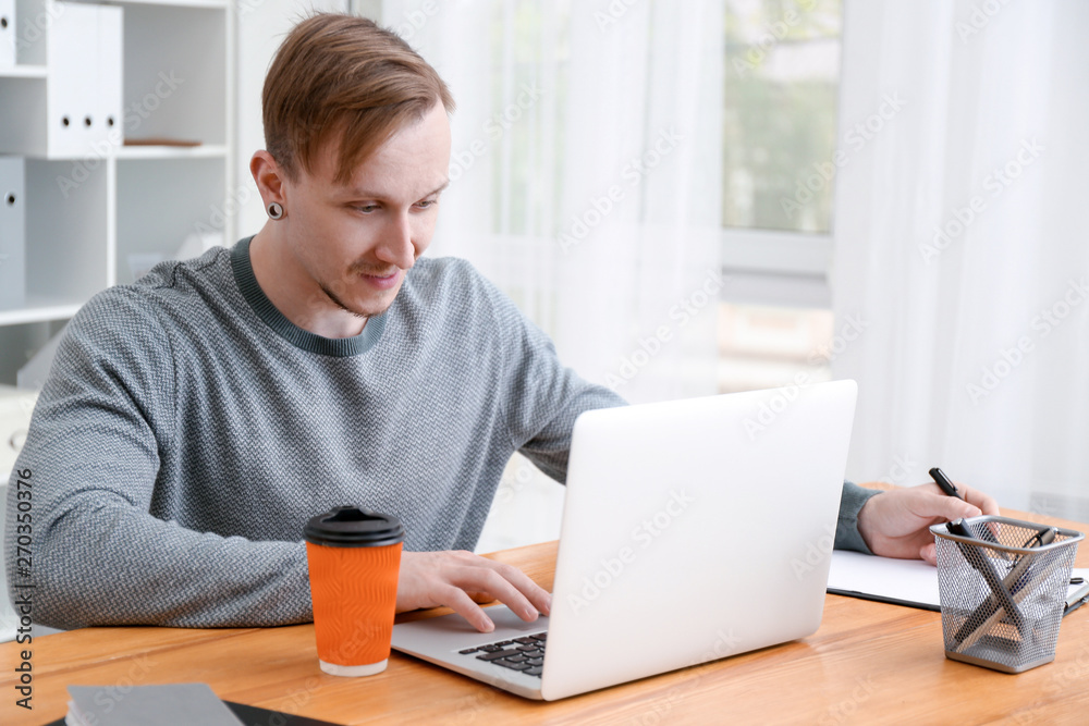 Handsome man working on laptop and drinking coffee at home Handsome man working on laptop and drinking coffee at home
