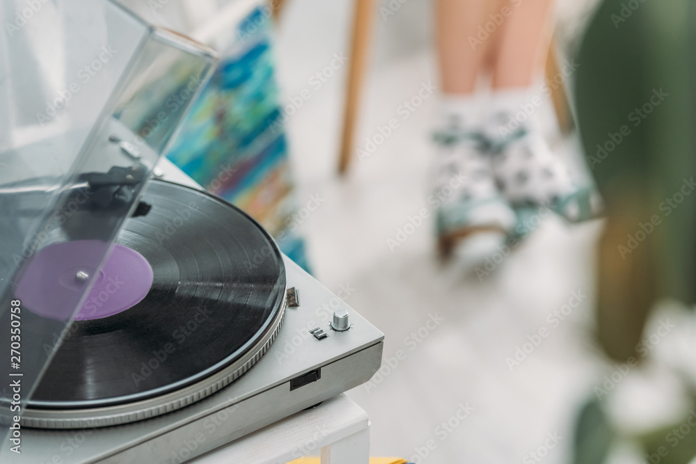 partial view of girl in dotted socks and record player with vinyl disc partial view of girl in dotted socks and record player with vinyl disc