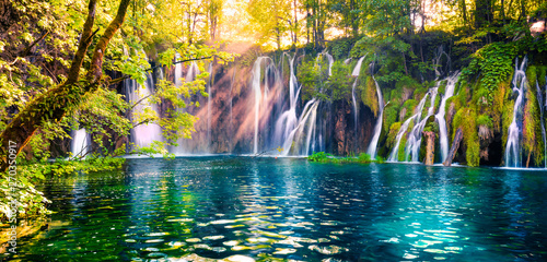 Fototapeta Naklejka Na Ścianę i Meble -  Last sunlight lights up the pure water waterfall on Plitvice National Park. Colorful spring panorama of green forest with blue lake. Great countryside view of Croatia, Europe. 