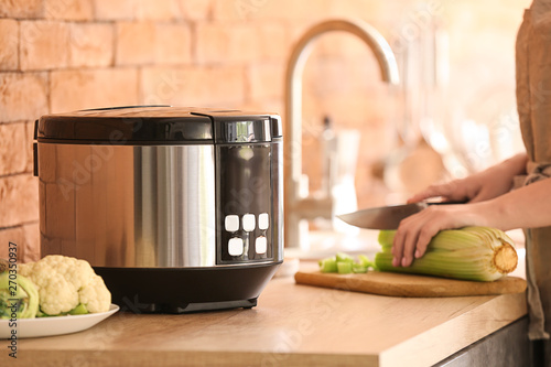 Woman using modern multi cooker in kitchen photo