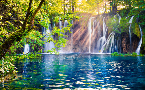 Fototapeta Naklejka Na Ścianę i Meble -  Last sunlight lights up the pure water waterfall on Plitvice National Park. Colorful spring scene of green forest with blue lake. Great countryside view of Croatia, Europe. 