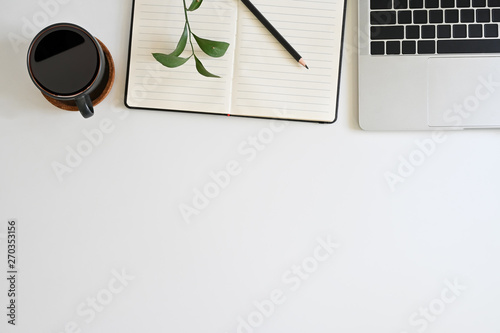 Office desk top view table with laptop, coffee, plant, notebook and pencil