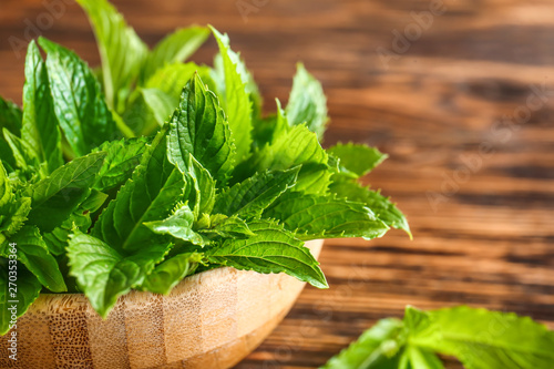 Bowl with fresh green mint on wooden table, closeup