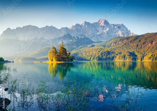 Naklejka Great summer sunrise on Eibsee lake with Zugspitze mountain range. Sunny outdoor scene in German Alps, Bavaria, Germany, Europe. Beauty of nature concept background.