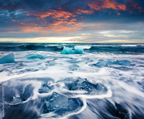 Blocks of ice washed by the waves on Jokulsarlon beach. Dramatic summer sunrise in Vatnajokull National Park, southeast Iceland, Europe. Beauty of nature concept background.