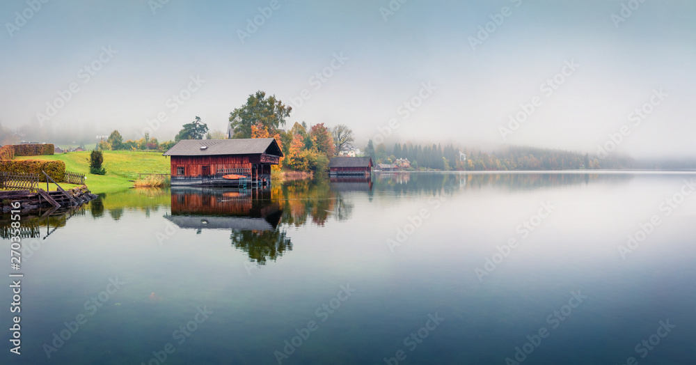 Foggy autumn panorama of Altausseer See lake. Mystical morning view of Altaussee village, district of Liezen in Styria, Austria. Beauty of countryside concept background.