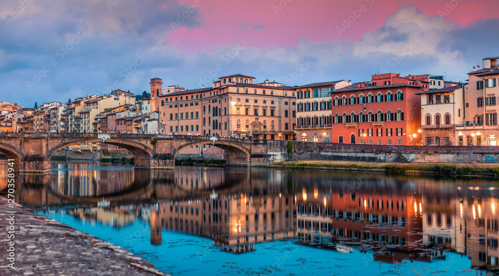 Spectacular medieval arched St Trinity bridge (Ponte Santa Trinita) over Arno river. Colorful spring sunset in Florence, Italy, Europe. Traveling concept background.