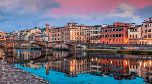 Spectacular medieval arched St Trinity bridge (Ponte Santa Trinita) over Arno river. Colorful spring sunset in Florence, Italy, Europe. Traveling concept background.