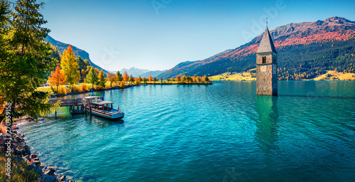 Fototapeta Naklejka Na Ścianę i Meble -  Panoramic autumn view of Tower of sunken church in Resia lake. Sunny morning scene of Italian Alps, South Tyrol, Italy, Europe. Traveling concept background.
