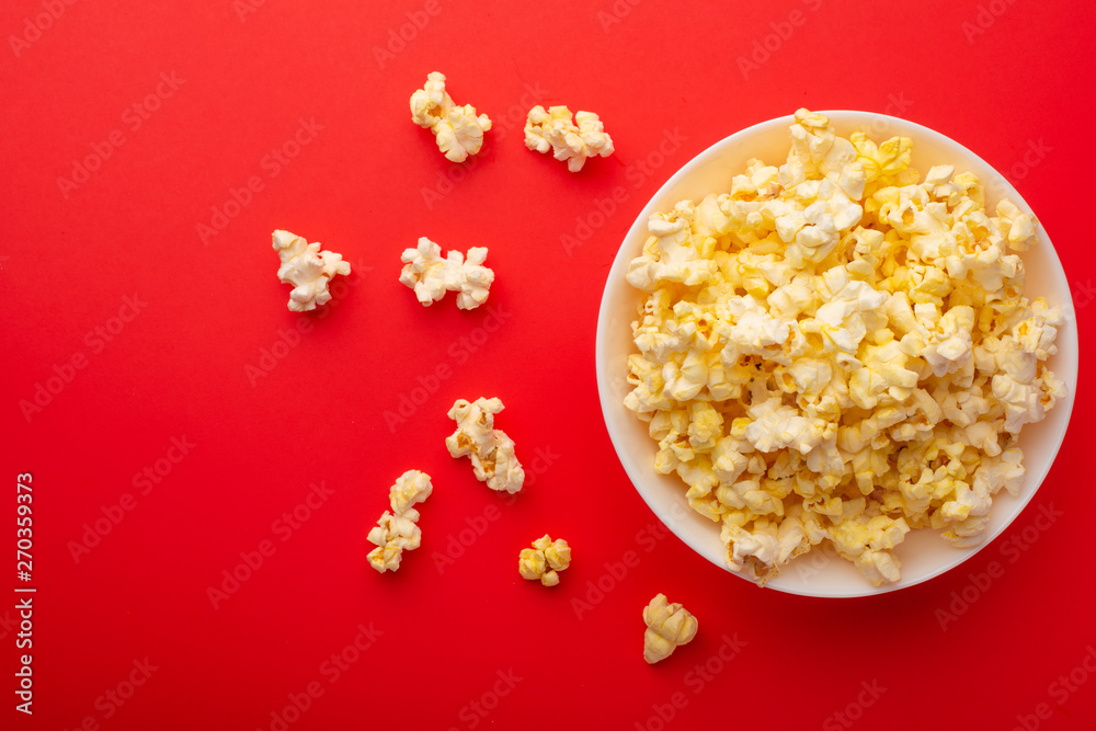 plate with popcorn on a red bright background. movie viewing concept, weekend getaway, with space plate with popcorn on a red bright background. movie viewing concept, weekend getaway, with space