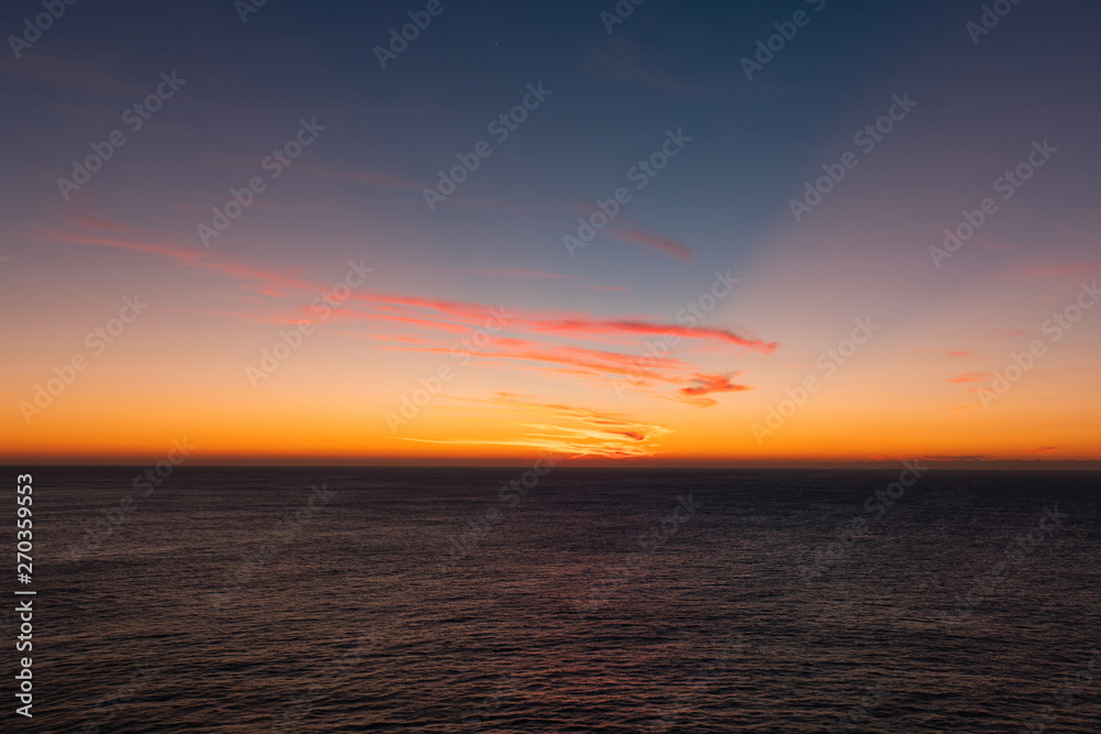 Warm colorful sunrise sky over the ocean horizon.
