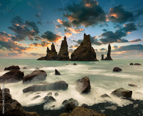 Dramatic seascape of Reynisdrangar cliffs in the Atlantic ocean. Fabulous summer sunset in south Iceland, Vic village location, Europe. Beauty of nature concept background. photo