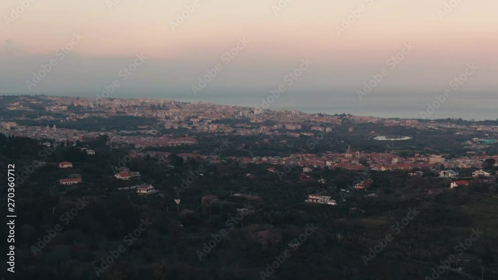 Aerial approaching view of the town of Acireale with the east coast of Sicily in the background at sunset Aerial approaching view of the town of Acireale with the east coast of Sicily in the background at sunset