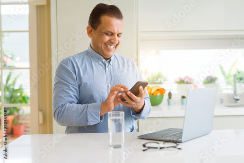Middle age man working with laptop and using smartphone