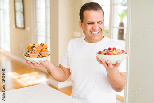 Middle age man trying to choose between healthy food and junk food