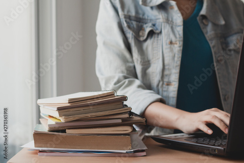 stack of book and document on office desk with woman using laptop for working. 