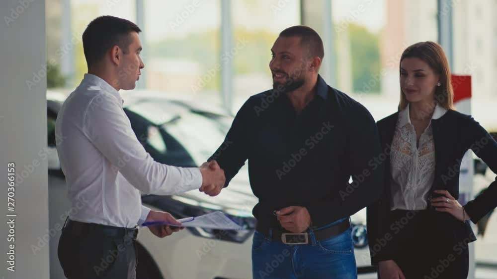 Happy couple just got a keys from a new car in car showroom Happy couple just got a keys from a new car in car showroom