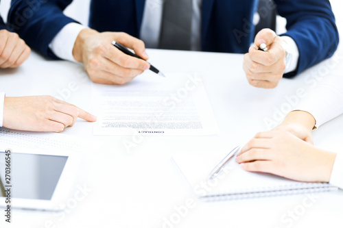 Group of business people and lawyers discussing contract papers sitting at the table, close-up. Successful teamwork, cooperation and agreement concepts