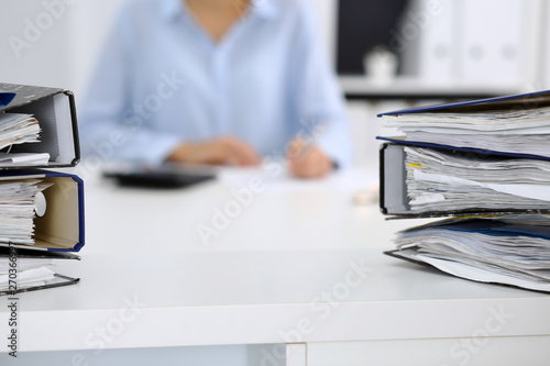 Binders with papers are waiting to be processed by business woman or bookkeeper back in blur. Internal Audit and tax concept