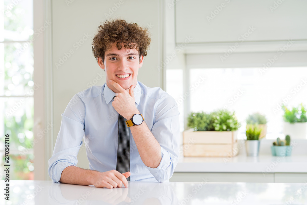 Young business man wearing a tie looking confident at the camera with smile with crossed arms and hand raised on chin. Thinking positive.