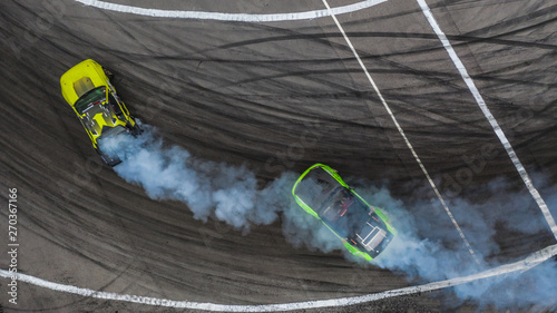 Aerial top view photo of blurred two professional driver drifting car on asphalt track, car drifting battle.