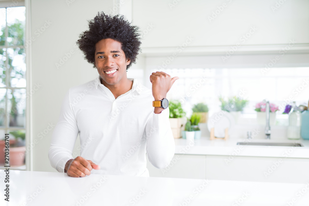African American man smiling with happy face looking and pointing to the side with thumb up. African American man smiling with happy face looking and pointing to the side with thumb up.