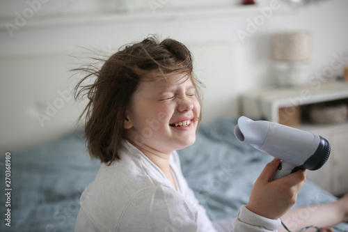 Girl, 8 years old dries her hair with hair dryer