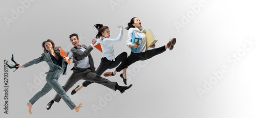 Happy office workers jumping and dancing in casual clothes or suit with folders isolated on studio background. Business, start-up, working open-space, motion and action concept. Creative collage.