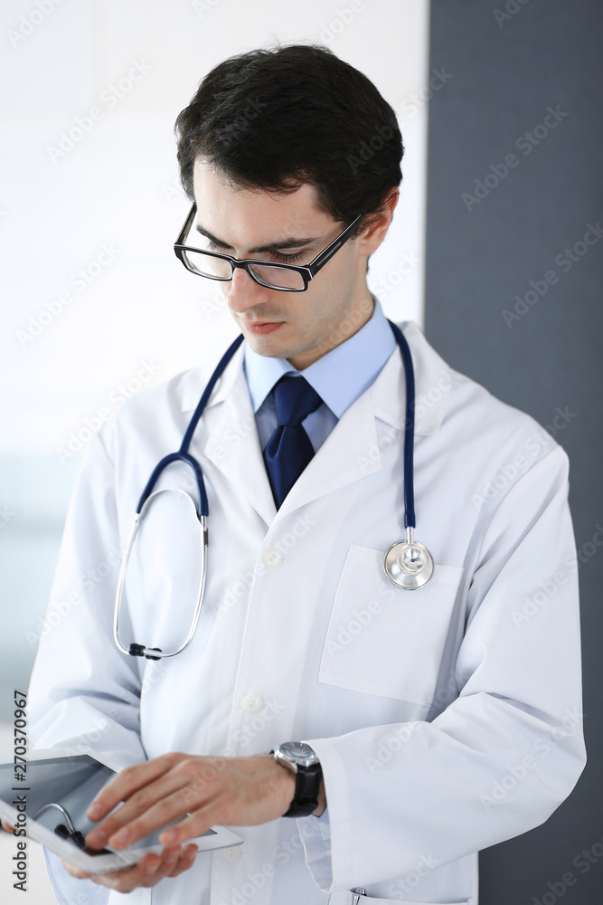 Doctor man using tablet computer for network research or virtual disease treatment. Perfect medical service in clinic. Modern medicine, medic data and healthcare concepts Doctor man using tablet computer for network research or virtual disease treatment. Perfect medical service in clinic. Modern medicine, medic data and healthcare concepts