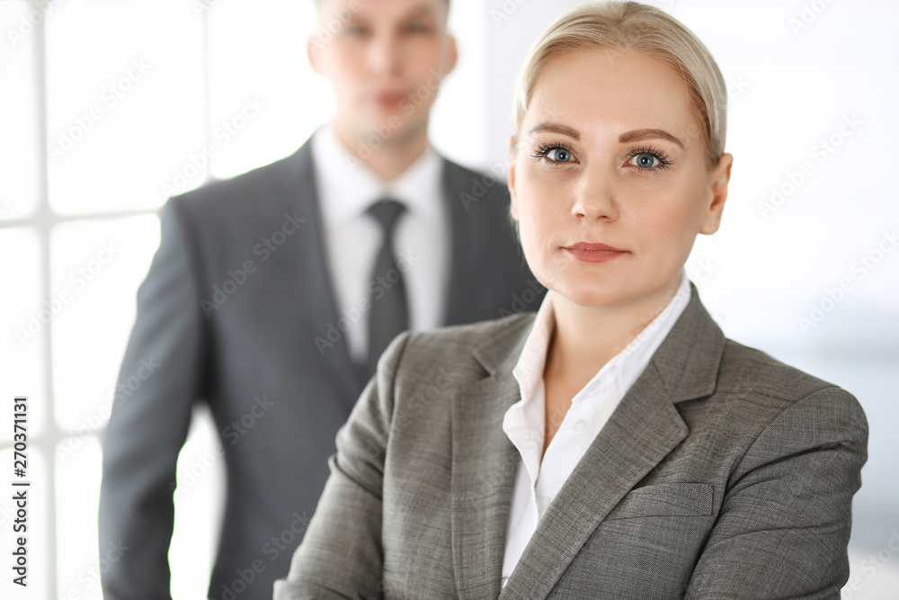 Business woman standing straight with colleague businessman in office, headshot. Success and corporate partnership concept Business woman standing straight with colleague businessman in office, headshot. Success and corporate partnership concept