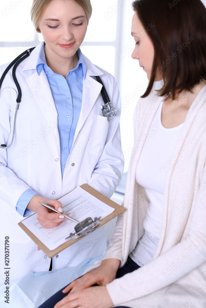 Young woman doctor and patient at medical examination at hospital office. Blue color blouse of therapist looks good. Medicine and healthcare concept Young woman doctor and patient at medical examination at hospital office. Blue color blouse of therapist looks good. Medicine and healthcare concept