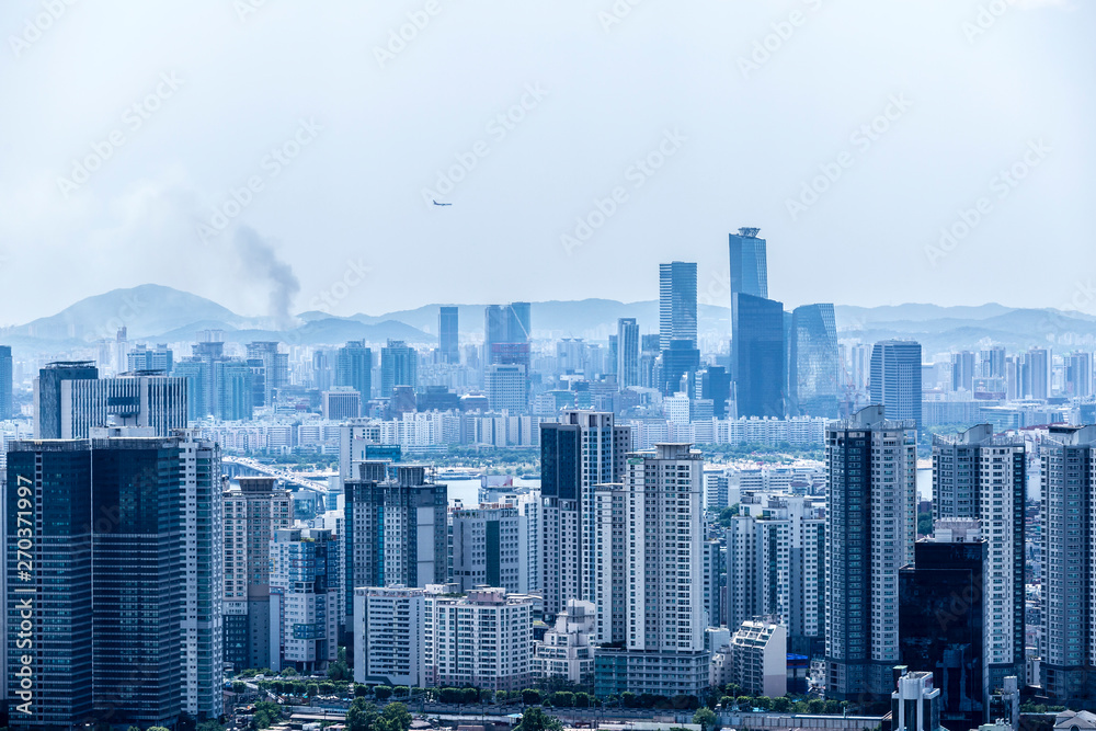 Blue tone cityscape of Seoul from the Namsan Mountain, South Korea. Airplane flying over the city