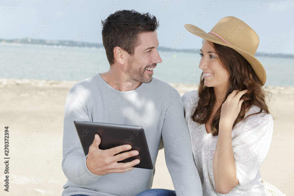 young couple using a digital tablet at seaside town young couple using a digital tablet at seaside town