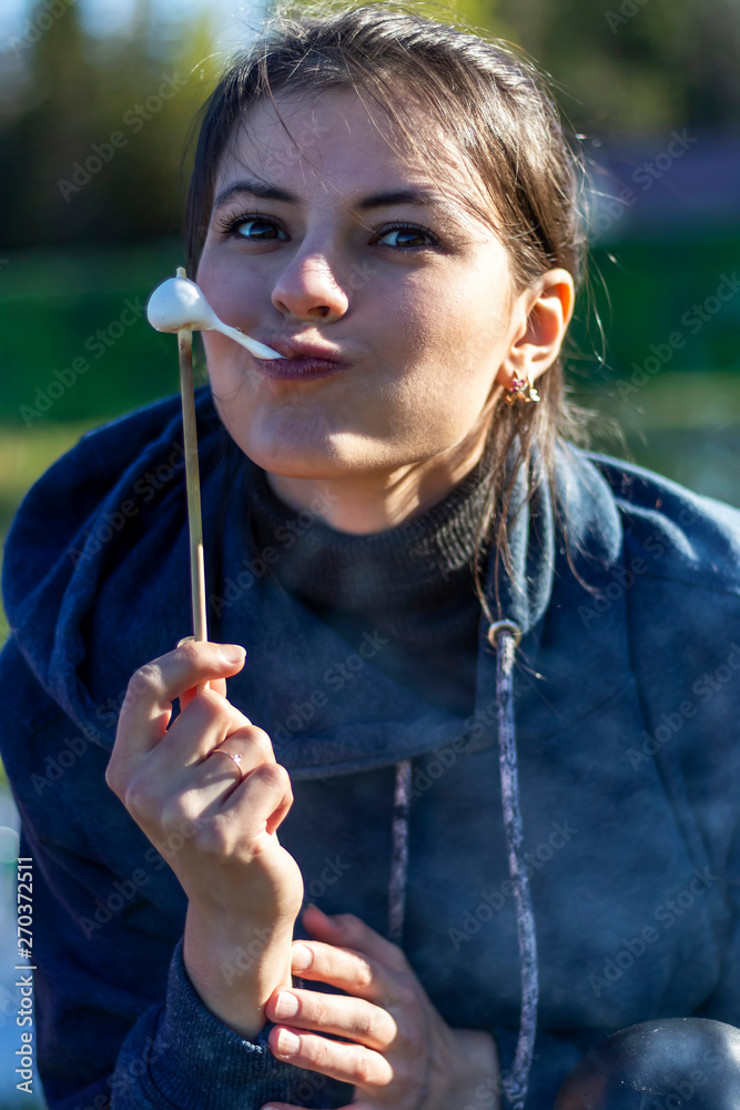 The girl eats marshmallow roasted on a stick in the forest The girl eats marshmallow roasted on a stick in the forest