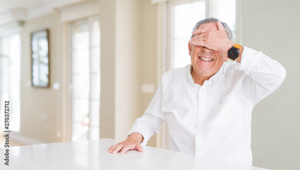Handsome senior man at home smiling and laughing with hand on face covering eyes for surprise. Blind concept. Handsome senior man at home smiling and laughing with hand on face covering eyes for surprise. Blind concept.