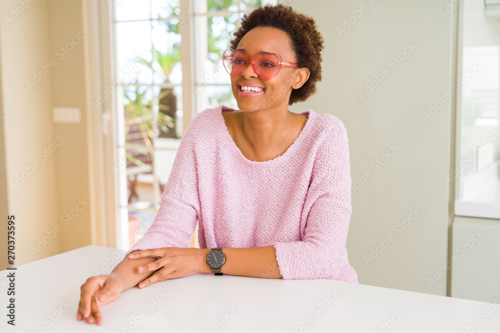 Beautiful young african woman with afro hair wearing funny pink heart glasses Beautiful young african woman with afro hair wearing funny pink heart glasses