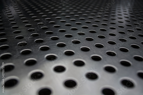 Gray monophonic background with big quantity of holes in a metal plate. Surface. Texture.