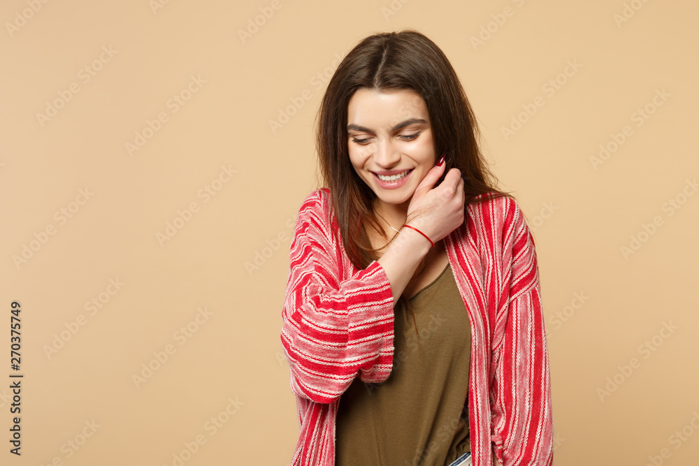Portrait of smiling young woman in casual clothes looking down keeping hand near face isolated on pastel beige wall background in studio. People sincere emotions lifestyle concept. Mock up copy space. Portrait of smiling young woman in casual clothes looking down keeping hand near face isolated on pastel beige wall background in studio. People sincere emotions lifestyle concept. Mock up copy space.